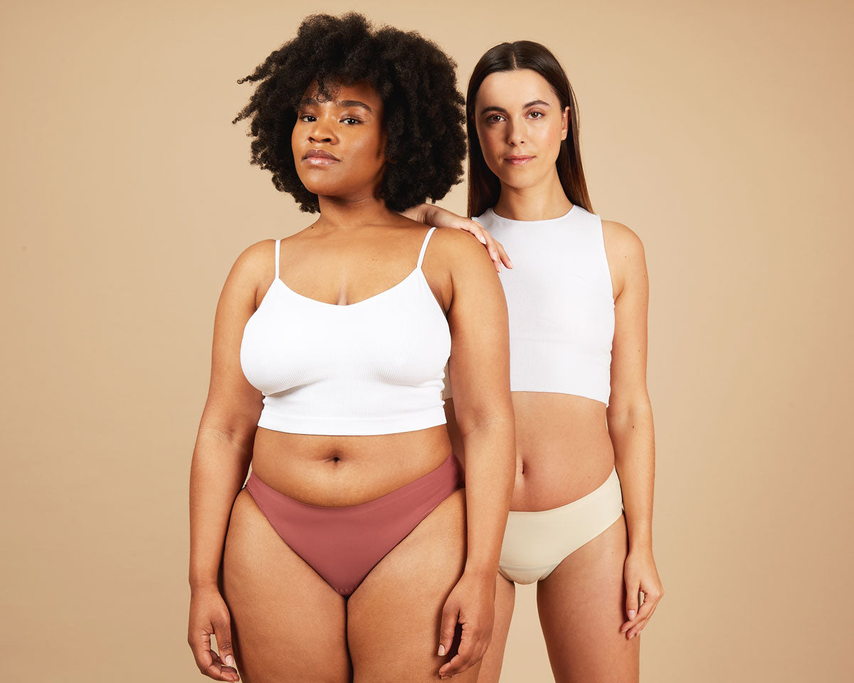 Two women wearing seamless period underwear and white vests, showcasing leakproof confidence and period comfort.