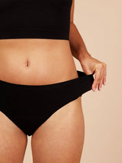 Close-up of woman wearing black seamless period pants highlighting the stretchy fabric